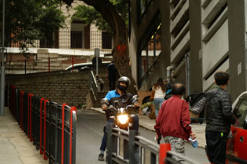 a man riding a motorcycle down a street next to a fence