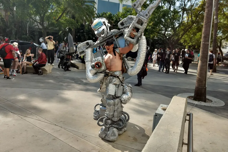 a man in a robot suit holding a giant metal object in his hands