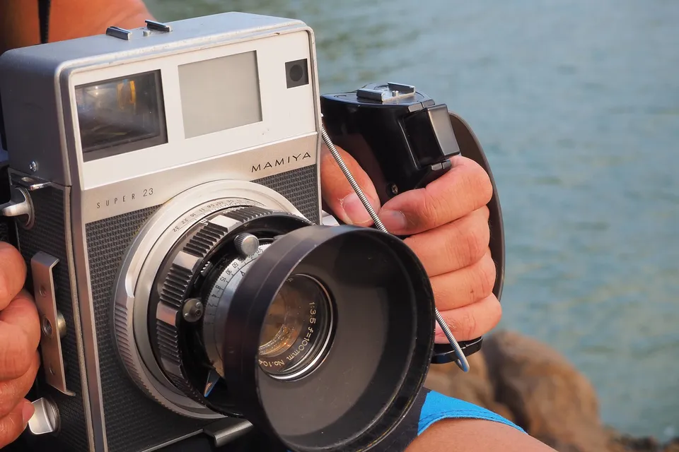 Front of Mamiya Press Super 23 with 100mm f/3.5 lens and hand grip being held in golden hour light