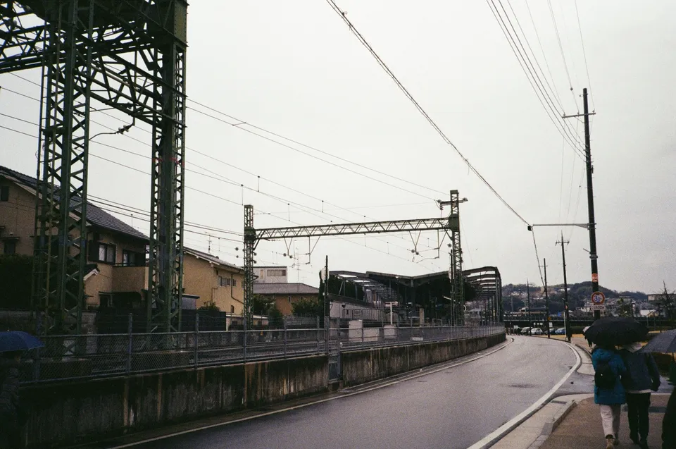 a couple of people walking down a street next to a train station